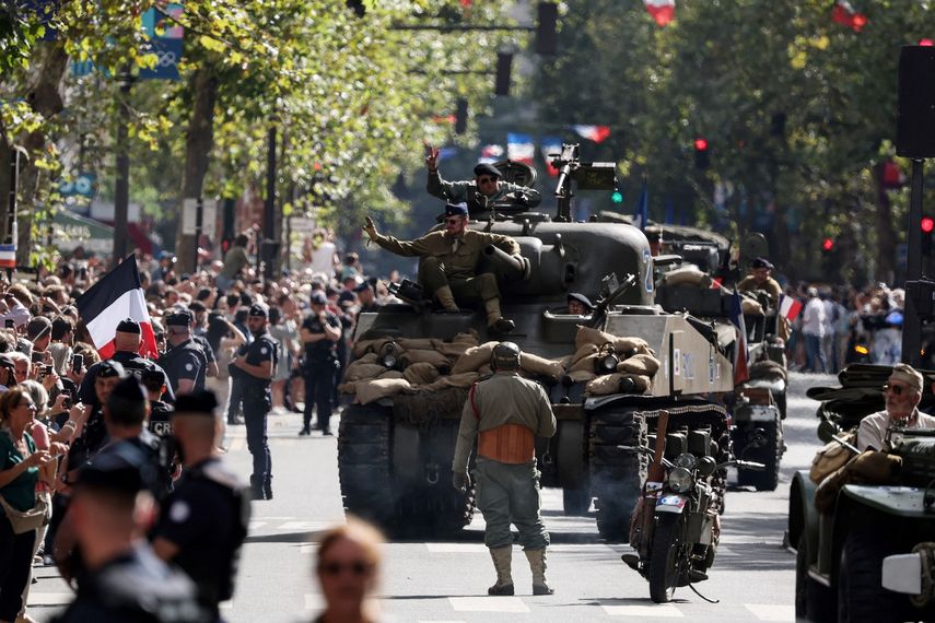 Recreadores vestidos con uniformes de guerra desfilan en vehículos militares antiguos durante una recreación que conmemora el 80º aniversario de la liberación de París de los alemanes durante la Segunda Guerra Mundial, en París el 25 de agosto de 2024.&nbsp;
