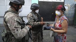 Una mujer explica a los soldados que est&aacute; buscando alcohol en farmacias, antes de que la dejen continuar su camino, en el tercer d&iacute;a del estado de emergencia en Lima, Per&uacute;, el mi&eacute;rcoles 18 de marzo de 2020.