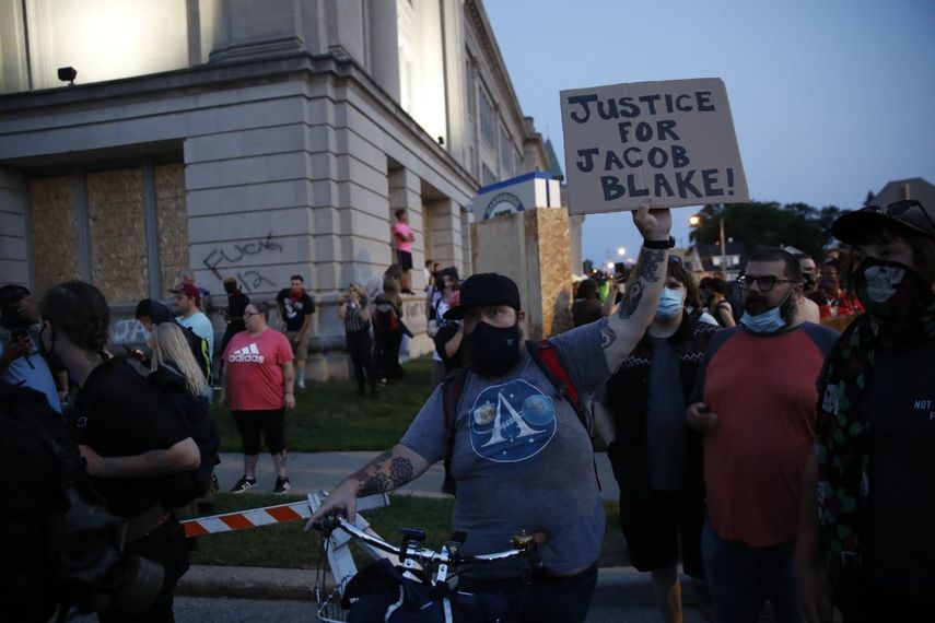 Manifestante sostiene un cartel mientras marchan frente a la Corte de Justicia del Condado durante las manifestaciones contra el tiroteo a Jacob Blake en Kenosha, Wisconsin, el 25 de agosto de 2020.
