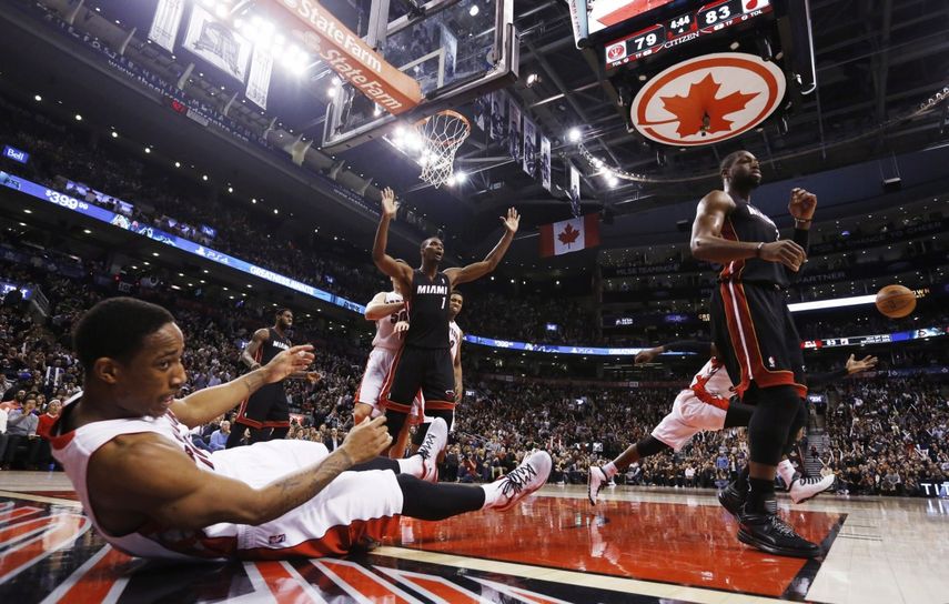 DeMar DeRozan cae ante la acción de Chris Bosh y Dwayne Wade. (AP)
