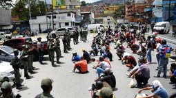 Miembros de la Guardia Nacional Bolivariana explican el uso de la mascarilla a peatones y vendedores ambulantes en Caracas, Venezuela.