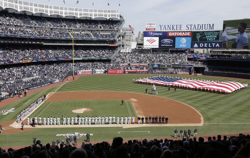 En foto de archivo del 28 de marzo del 2019, despliegan la bandera durante el Himno Nacional en el primer día de juegos de los Yanquis de Nueva York ante los Orioles de Baltimore. El 9 de abril del 2020 Forbes estimó que los Yanquis son el equipo más valioso de la MLB con 5 mil millones de dólares.