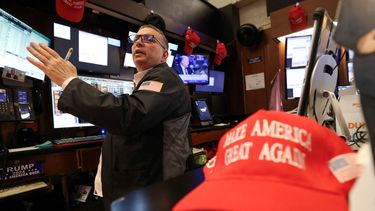 Un agente de la Bolsa de Nueva York y la imagen de una gorra alegórica al movimiento MAGA (Make America Great Again). Un agente de la Bolsa de Nueva York y la imagen de una gorra alegórica al movimiento MAGA (Make America Great Again).