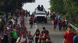 Miembros de la Guardia Nacional avanzan junto a migrantes por la carretera hacia la salida a Huixtla, estado de Chiapas, México, la madrugada del jueves 9 de junio de 2022.&nbsp;