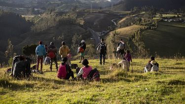 Un pequeño grupo de migrantes venezolanos observa la ruta Panamericana desde una colina de pasto en Urbina, Ecuador, el 27 de agosto de 2019.&nbsp;