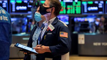 Agentes de la Bolsa de Nueva York miran una pantalla en el piso de remate.