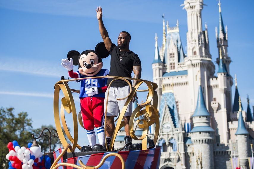 El corredor de los Patriots de Nueva Inglaterra, James White, saluda junto al ratón Mickey Mouse durante su participación en el tradicional desfile de gala de victoria de la Liga Nacional de Fútbol Americano (NFL) este lunes 6 de febrero 2017, frente al palacio de la calle principal del parque temático Magic Kingdom de Disney en Orlando, Florida.&nbsp;