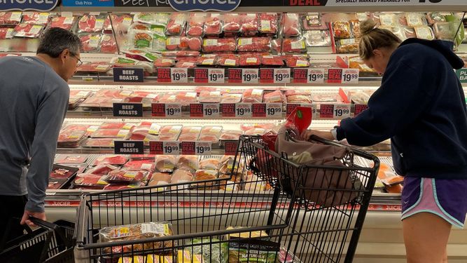 Dos personas observan los altos precios de la carne en un supermercado en Annapolis, Maryland.
