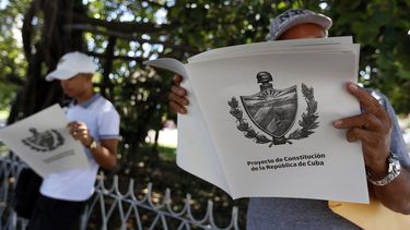 Dos personas leen en La Habana&nbsp;el tabloide con el texto del Proyecto de Constitución de la República de Cuba.