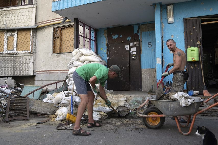 Viktor Lazar, a la derecha, limpia la calle ante su apartamento en el distrito de Saltivka tras ataques rusos en Járkiv, Ucrania, el 5 de julio de 2022.&nbsp;