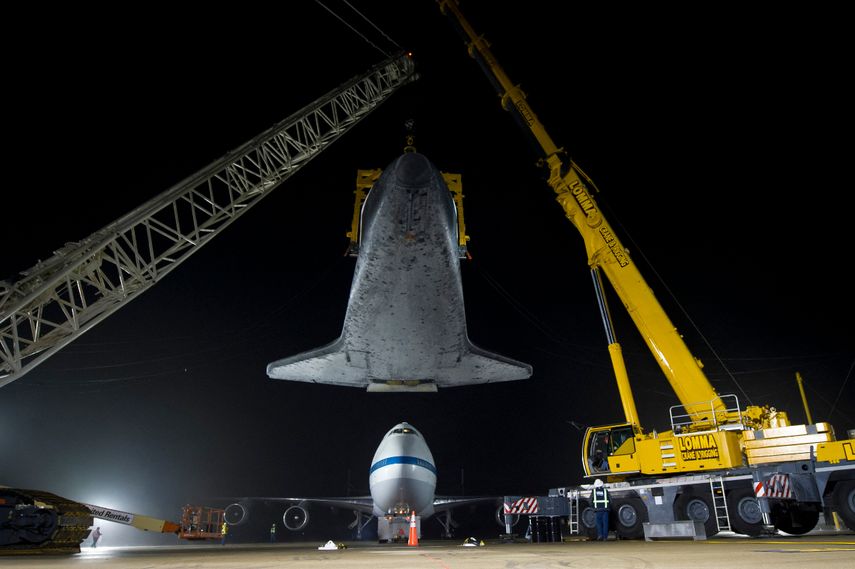 Esta foto de la NASA muestra el transbordador espacial Discovery, suspendido de una eslinga sostenida por dos grúas, mientras el 747 Shuttle Carrier Aircraft (SCA) de la NASA es empujado hacia atrás desde abajo en el Aeropuerto Internacional Washington-Dulles, el 19 de abril de 2012, en Sterling, Virginia.