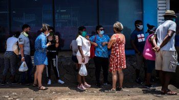 Afuera de una tienda estatal de comida, personas con mascarillas para protegerse del nuevo coronavirus esperan en línea para entrar en La Habana, Cuba, el martes 19 de mayo de 2020. 