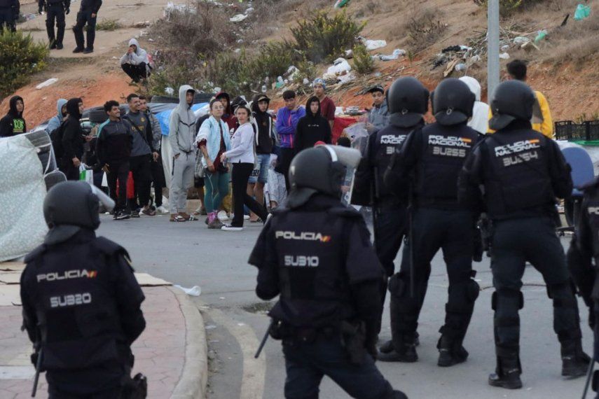 Oficiales de la Policía Nacional participan este domingo en una operación para desalojar las naves del Tarajal, en Ceuta, como consecuencia del elevado número de migrantes que se habían ubicado cerca de este espacio.&nbsp;