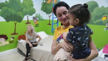 Isabel Bembow Tamayo sostiene a Liam Centeno, de 1 año, en el salón de clases de la escuela Iglesia Rescate que se convierte en un dormitorio para su familia, el martes 21 de febrero de 2023, en Hialeah, Florida.&nbsp; 