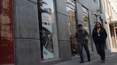 Dos personas caminan frente a la sede de un banco en Ciudad de México.