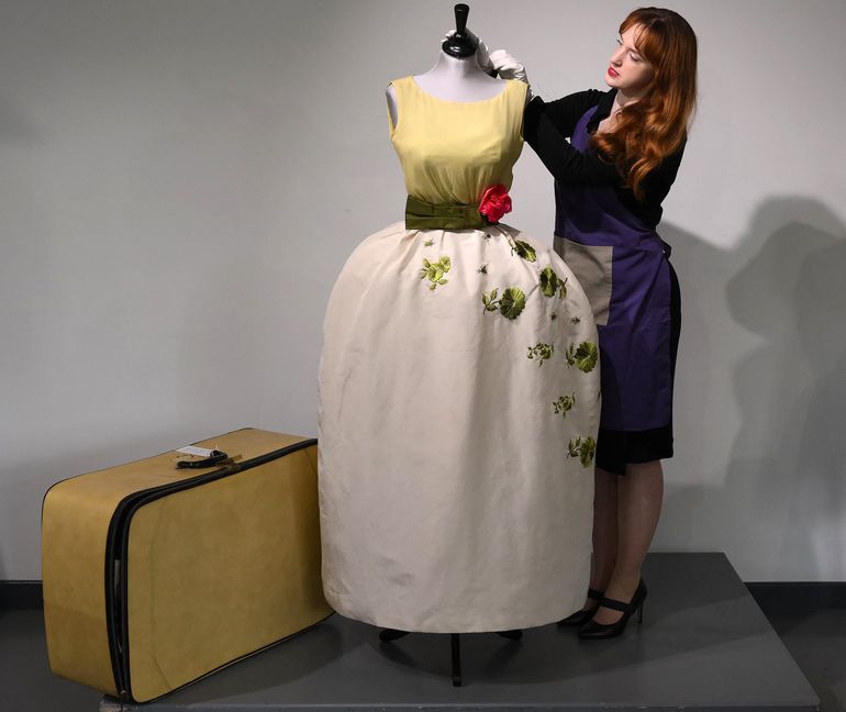 Una empleada posa con un vestido de Christian Dior usado por la actriz Elizabeth Taylor, recientemente descubierto con otros vestidos en una maleta, antes de su venta en Kerry Taylor Auctions, en Londres el 25 de noviembre de 2022.