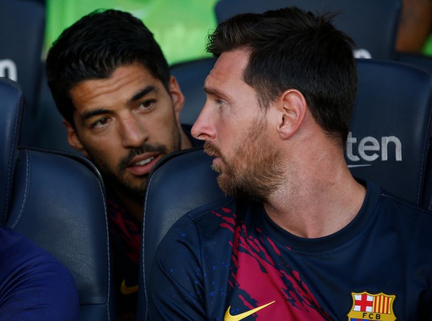  En imagen de archivo del domingo 4 de agosto de 2019, el argentino Lionel Messi, derecha, dialoga con su compañero Luis Suárez en la banca del Barcelona