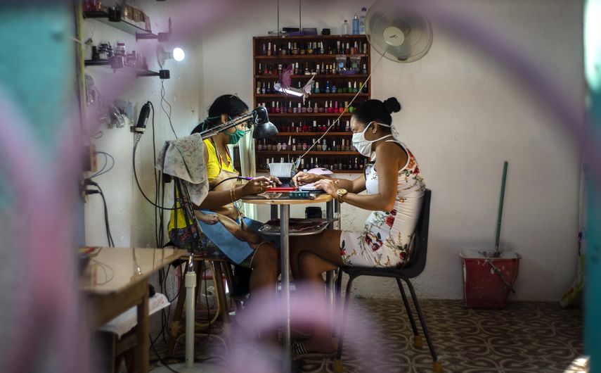 En esta imagen, tomada el 31 de marzo de 2020, dos mujeres, equipadas con mascarilla como medida de precauci&oacute;n contra el nuevo coronavirus, en un sal&oacute;n de manicura en una casa en La Habana, Cuba. Las autoridades cubanas exigen que cualquiera que salga de su casa lleve mascarilla.&nbsp;&nbsp;