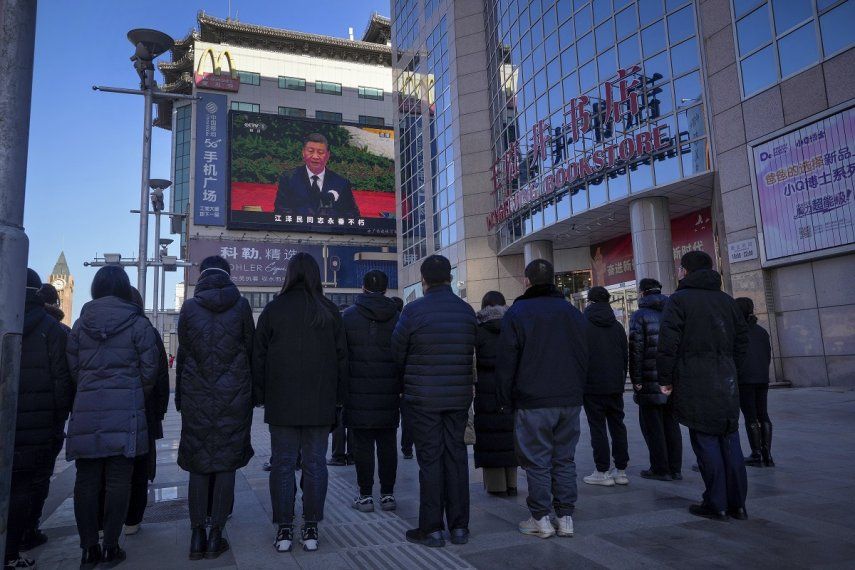 Gente mirando una emisión en vivo del funeral del expresidente de China Jiang Zemin, en la que el actual presidente de China, Xi Jinping, ofrece un discurso, en una pantalla en la calle comercial de Wangfujing en Beijing, el martes 6 de diciembre de 2022.
