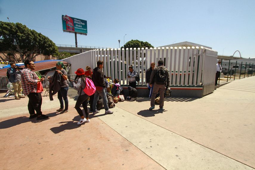 Migrantes centroamericanos esperan para cruzar hacia Estados Unidos desde la línea ubicada en la ciudad del El Chaparral, en la fronteriza Tijuana (México). 