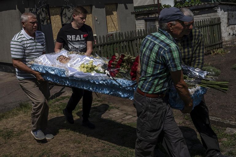 Hombres cargan el cuerpo sin vida de Anna Protensko, de 35 años, quien murió en un ataque de cohetes rusos, el lunes 18 de julio de 2022, en Pokrovks, en el este de Ucrania. 
