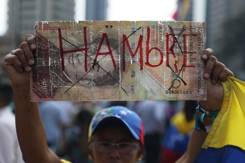Una mujer muestra un billete de cien bolívares a gran escala con la palabra hambre durante una manifestación opositora en Caracas, Venezuela, este 10 de abril de 2019.