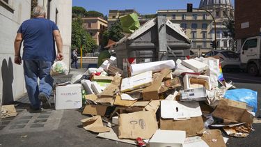 Un hombre pasa junto a una pila de basura con la cúpula de la basílica de San Pedro del Vaticano al fondo, en Roma, el 24 de junio de 2019. 