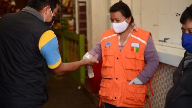 Una mujer aplica desinfectante de manos a un cliente a la entrada de un mercado municipal en la ciudad guatemalteca de San Marcos.