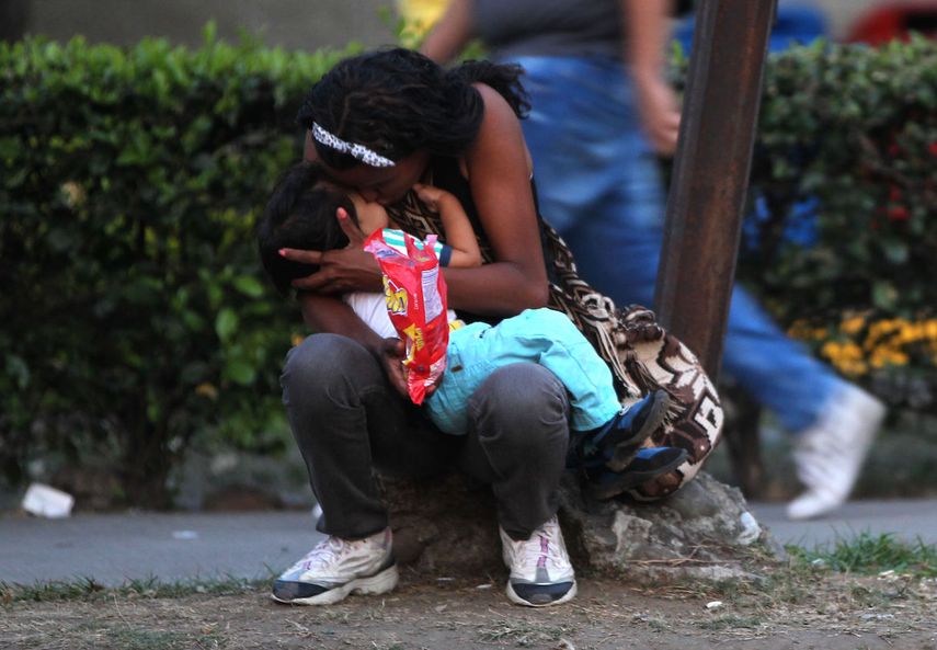 Una mujer venezolana abraza a su hijo en una acera de Colombia mientras espera para seguir su camino hacia Perú.&nbsp;