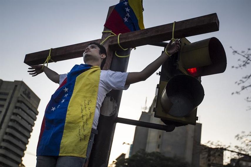 Un hombre se amarra simulando una crucifixión a modo de protesta contra el Gobierno venezolano, en el semáforo de una plaza hoy, miércoles 4 de marzo de 2015, en Caracas (Venezuela). (Foto EFE)
