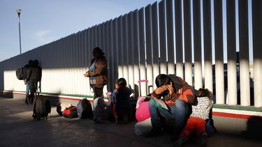 En esta imagen del 25 de enero de 2019, un migrante se sienta al lado de sus hijos mientras esperan a que les llamen para solicitar asilo en Estados Unidos, junto al muro fronterizo en Tijuana, México.
