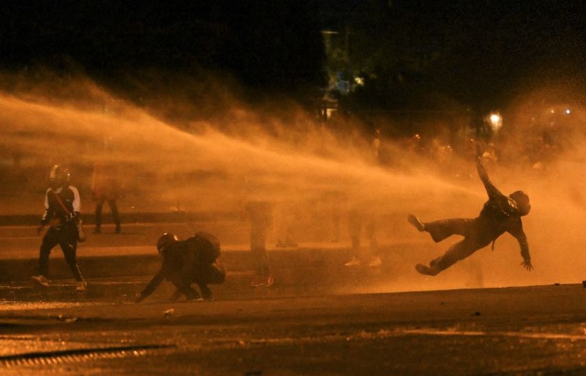 Un manifestante cae al ser alcanzado por un cañón de agua durante los enfrentamientos con la policía antidisturbios en medio de las continuas protestas contra el gobierno del presidente colombiano Iván Duque en Bogotá el 12 de junio de 2021.&nbsp;
