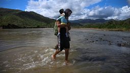 Hombre camina entre las agua con un bebé en brazos tras el paso del huracán Melissa. Cuba.&nbsp;