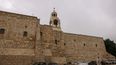 Un peregrino camina frente a la Iglesia de la Natividad en la ciudad ocupada de Belén, en Cisjordania, el 13 de diciembre de 2023, menos de dos semanas antes de Navidad, en medio de continuas batallas entre Israel y Hamás, en Gaza.