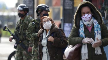 Soldados patrullan mientras dos mujeres esperan autobuses el lunes 1 de junio de 2020 en el &aacute;rea Kennedy de Bogot&aacute;, Colombia.