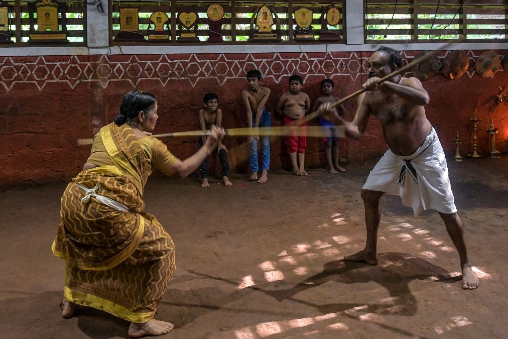 Esta fotografía muestra a Meenakshi Amma (izquierda) junto con su hijo Sajeev Kumar, practicantes y maestros de Kalaripayattu, un arte marcial tradicional originado en Kerala, en su escuela familiar. Esta fotografía muestra a Meenakshi Amma (izquierda) junto con su hijo Sajeev Kumar, practicantes y maestros de Kalaripayattu, un arte marcial tradicional originado en Kerala, en su escuela familiar.