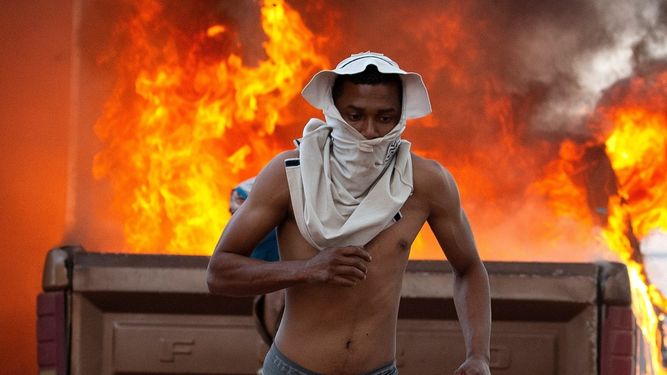 Una persona corre durante enfrentamientos entre manifestantes y miembros de la Guardia Nacional Bolivariana de&nbsp;Venezuela&nbsp;este sábado en el paso fronterizo ubicado en la localidad de Pacaraima (Brasil).
