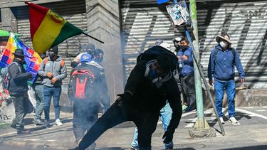 Un manifestante lanza una bandera nacional contra la policía antidisturbios durante una protesta en La Paz, el 18 de mayo de 2026, para exigir la renuncia del presidente de Bolivia, Rodrigo Paz.