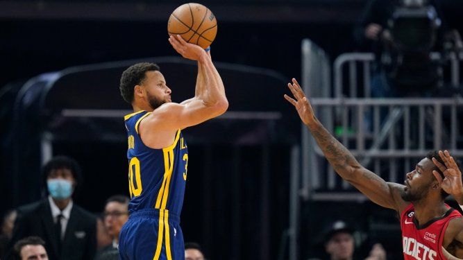 El base de los Warriors de Golden State, Stephen Curry, lanza un triple sobre el alero de los Rockets de Houston, Tari Eason, en el encuentro del sábado 3 de diciembre del 2022.