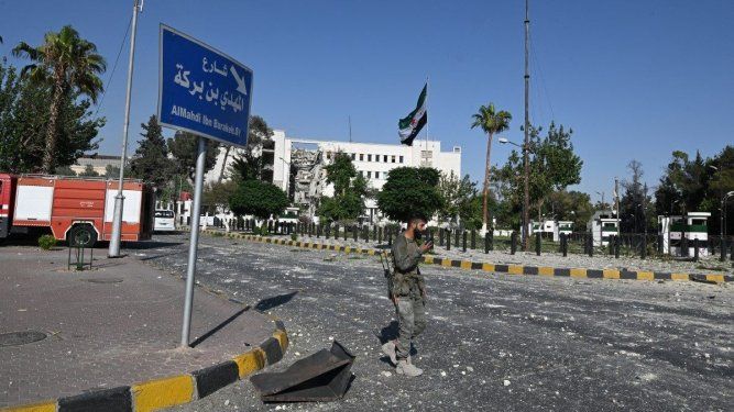 Un miembro de las fuerzas de seguridad sirias camina frente a la sede del ejército y del Ministerio de Defensa sirios en Damasco, gravemente dañada, tras los ataques israelíes del 16 de julio de 2025.&nbsp;&nbsp;