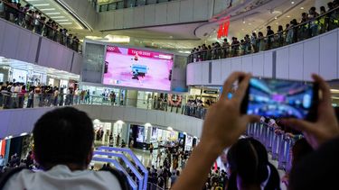 La gente en un centro comercial observa y anima a Doo Hoi-kem en Hong Kong el 27 de julio de 2021, mientras juega en un partido de tenis de mesa individual femenino en los Juegos Olímpicos de Tokio