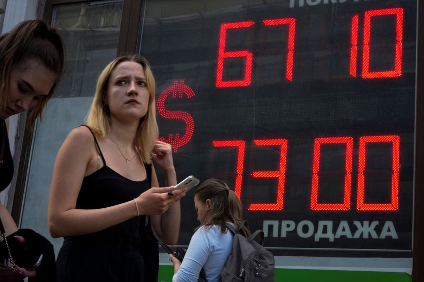 Una mujer camina junto a una pantalla que muestra el tipo de cambio del dólar estadounidense frente al rublo ruso, en San Petersburgo, Rusia.&nbsp;