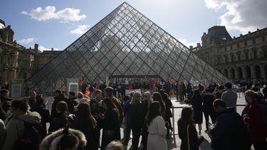 Visitantes esperan frente del Louvre mientras trabajadores de la industria cultural se manifiestan fuera del museo el lunes 27 de marzo de 2023 en París.