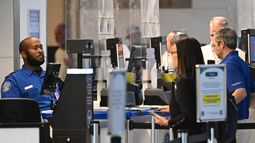 Oficial de la TSA verificando los documentos de identidad de los pasajeros en un punto de control de seguridad en el Aeropuerto Nacional Ronald Reagan, en Arlington, Virginia. Oficial de la TSA verificando los documentos de identidad de los pasajeros en un punto de control de seguridad en el Aeropuerto Nacional Ronald Reagan, en Arlington, Virginia.