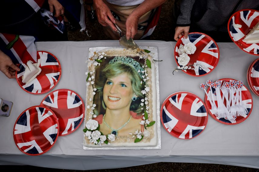Los visitantes cortaron un pastel que representaba a la difunta Diana de Gran Bretaña frente al Palacio de Kensington, en el centro de Londres, el 31 de agosto de 2022 durante una reunión para rendir un homenaje conmemorativo en el 25 aniversario de la muerte de la Princesa de Gales.
