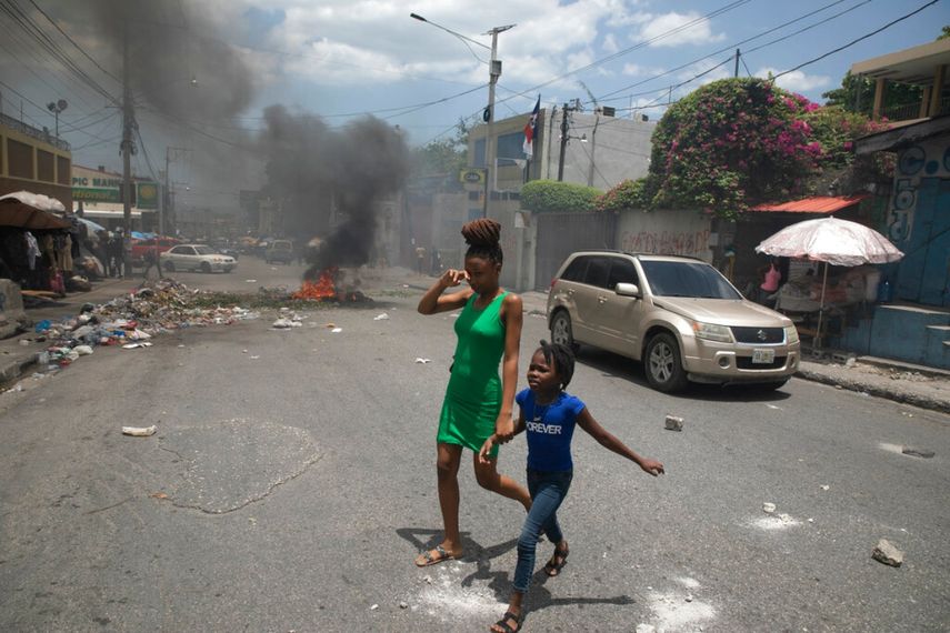 Una mujer y una niña pasan junto a barricadas en llamas colocadas por manifestantes que exigían la dimisión del primer ministro Ariel Henry, en Puerto Príncipe, Haití.