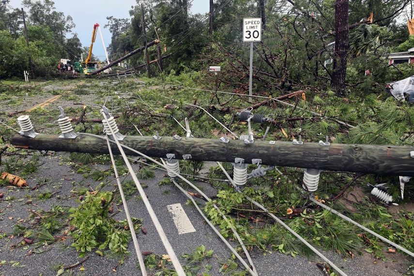 Cuadrillas de trabajadores retiran postes quebrados y cableado eléctrico derribado por los fuertes vientos, en una calle de Tallahassee, Florida.