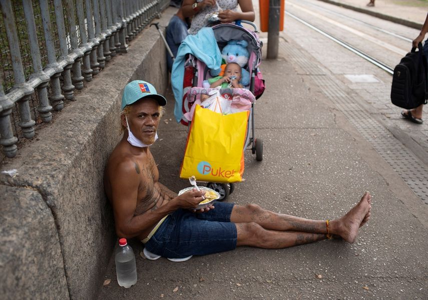 Un hombre mira a la cámara mientras come el almuerzo donado por la Fundación Leao XIII durante la pandemia de COVID-19, el miércoles 7 de abril de 2021, en Río de Janeiro, Brasil.