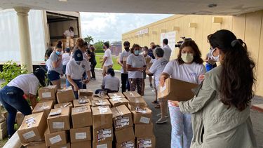 Voluntarios acomodan cajas de alimentos antes de repartirlas.