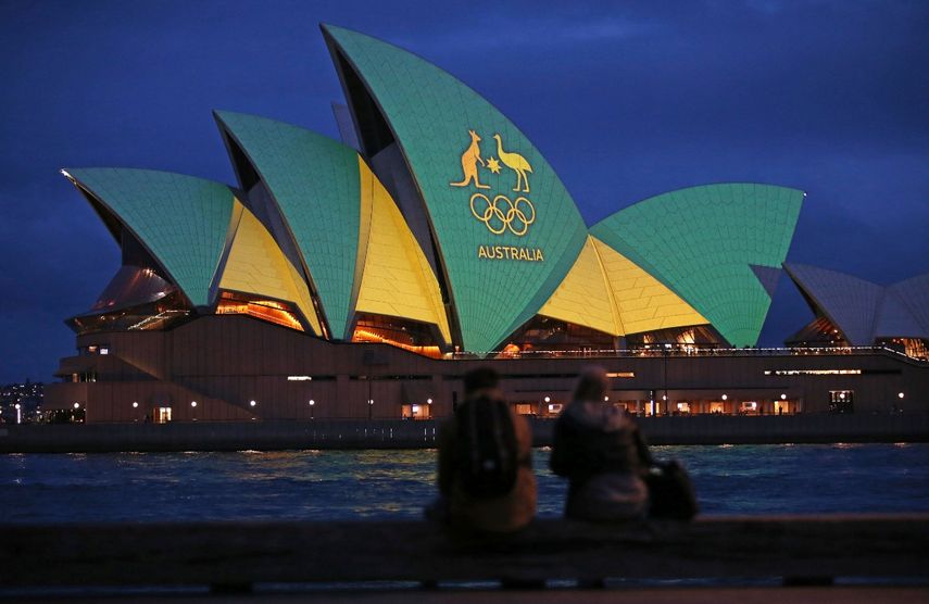 Una pareja observa la Ópera de Sídney iluminada con los colores del equipo australiano durante la campaña de Brisbane para ser sede de los Juegos Olímpicos del 2032&nbsp;